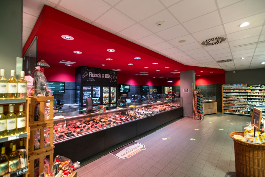 Bedientheke für Fleisch und Käse unter roter Decke, reich bestückt.