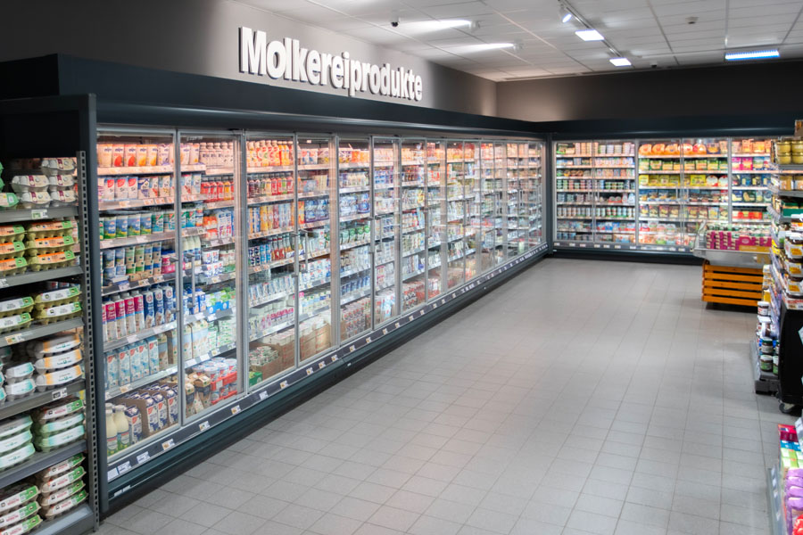 Lange Kühlregalreihe mit Milch- und Molkereiprodukten, Beschriftung „Molkereiprodukte“.