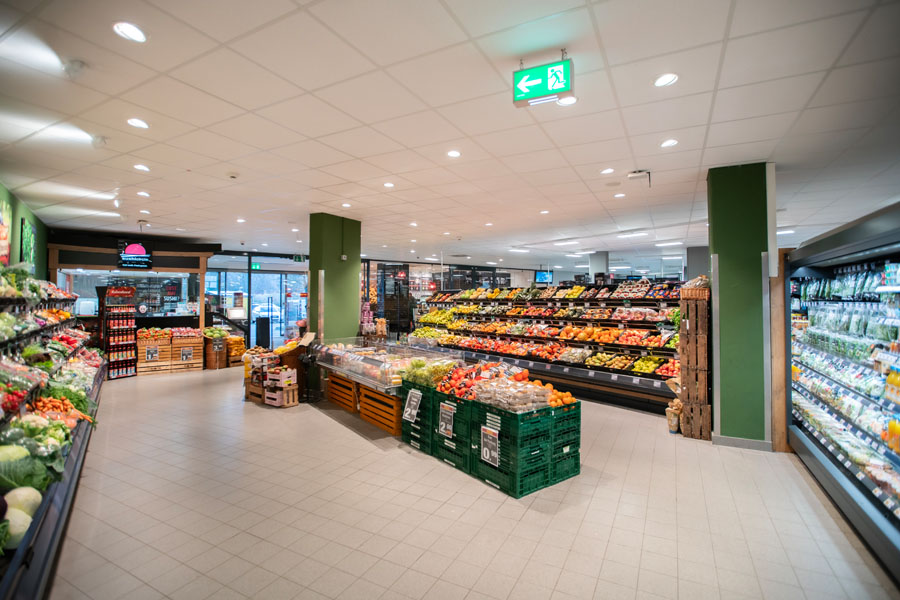 Helle Obst- und Gemüseabteilung mit Auslage und Kühlregalen im Supermarkt.